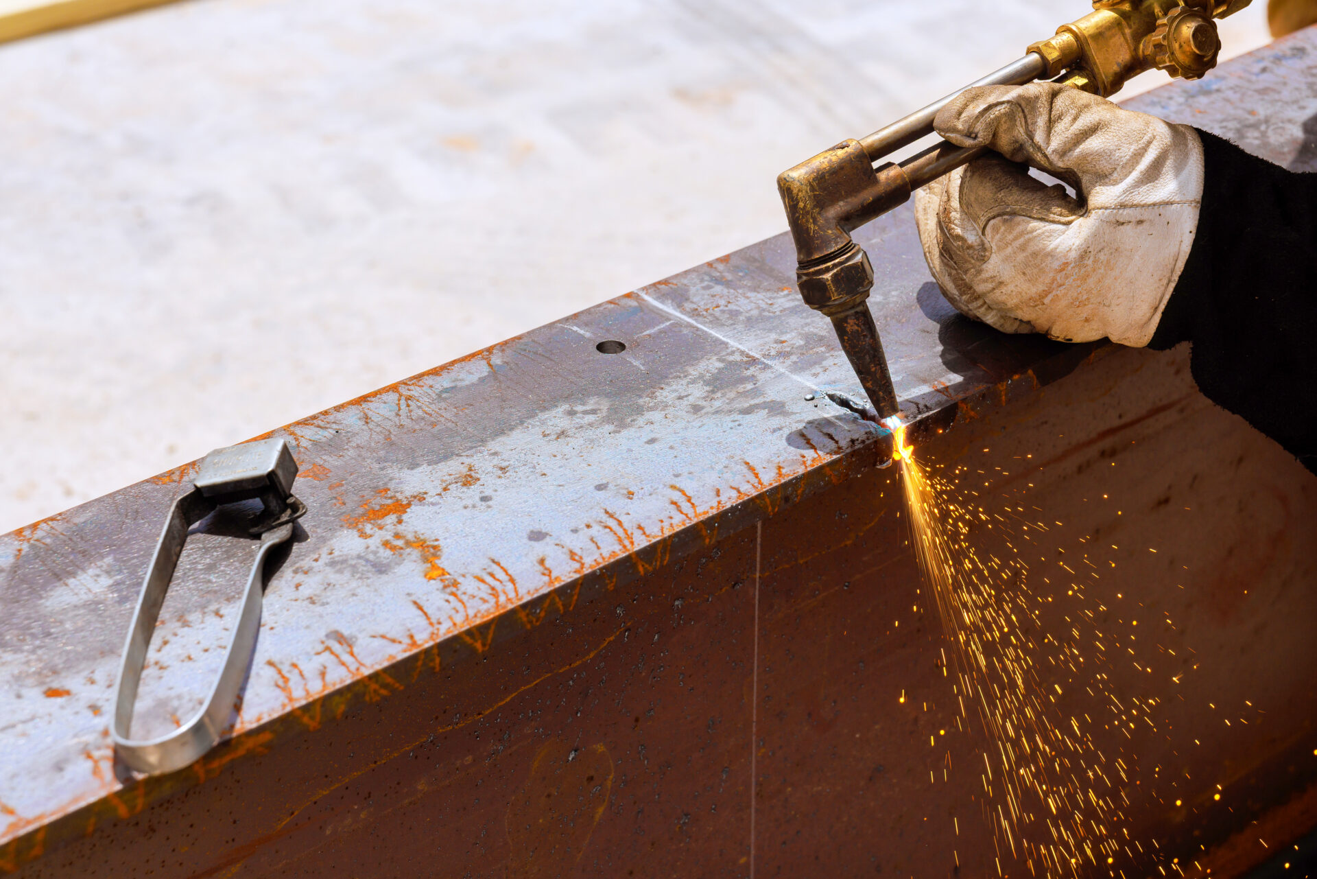 Industrial gas cutting torch cutting a thick steel beam with sparks